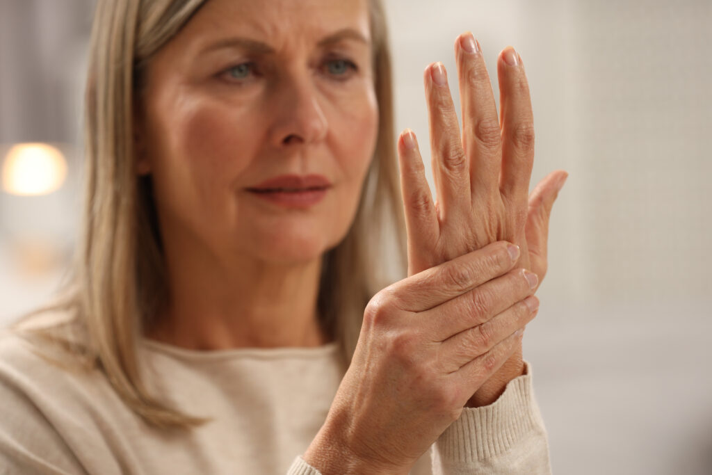Woman examining visible signs of aging and skin changes on the back of her hand.